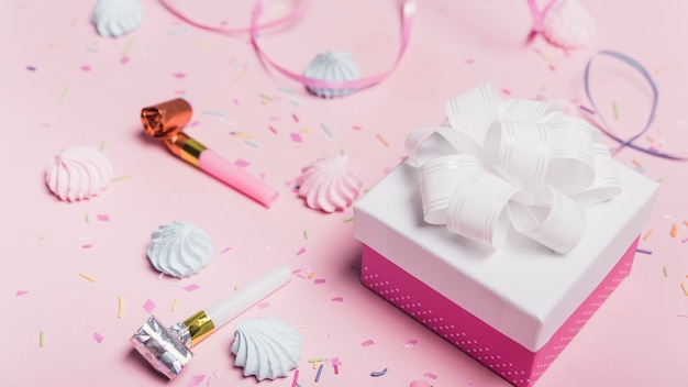 Gift boxes with candies; sprinkle; curl ribbon and party blowers on pink background