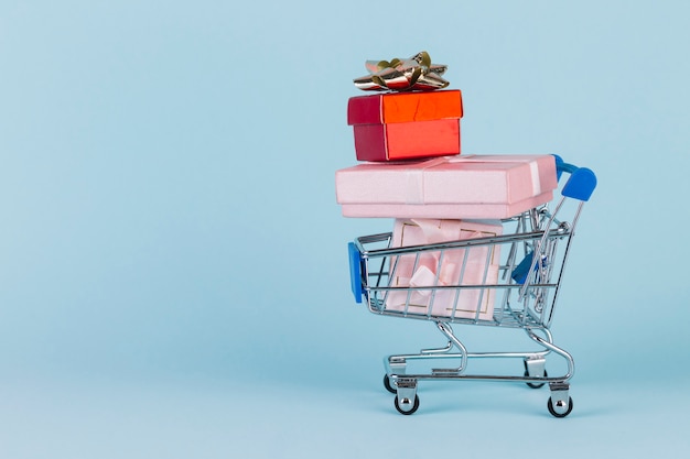 Free photo gifts stacked in shopping card on blue surface