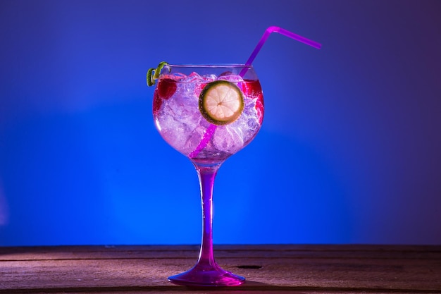 Free photo gin tonic with raspberries and lime on blue background