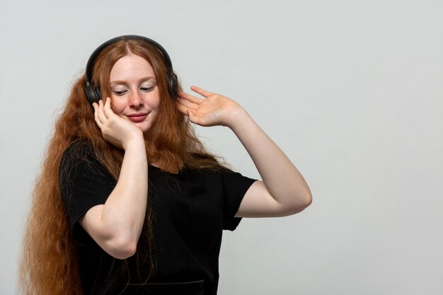 ginger lady listening to music in black dress on grey