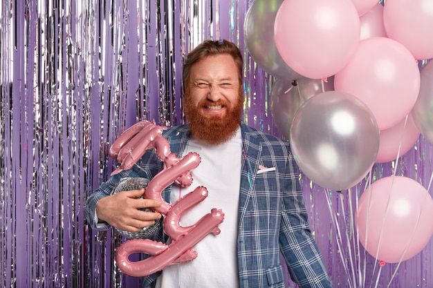 Ginger man at party holding disco globe and balloons