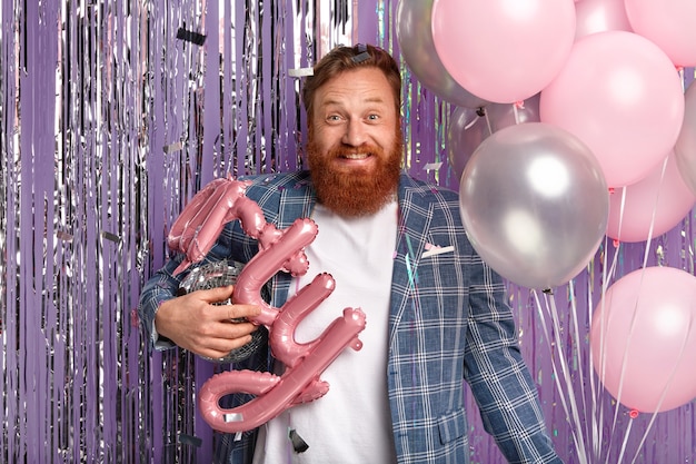 Ginger man at party holding disco globe and balloons