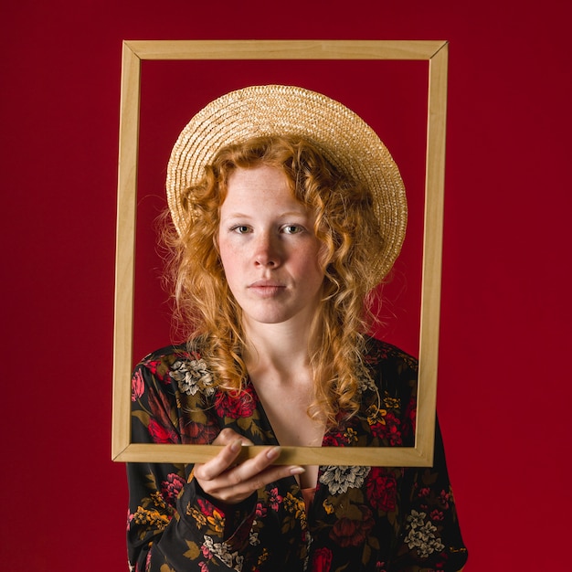 Free photo ginger thoughtful young woman holding picture frame