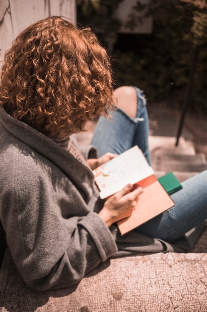 Free photo ginger woman holding book on stair