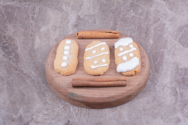 Free Photo gingerbread christmas cookies with cinnamon sticks on round wooden board.