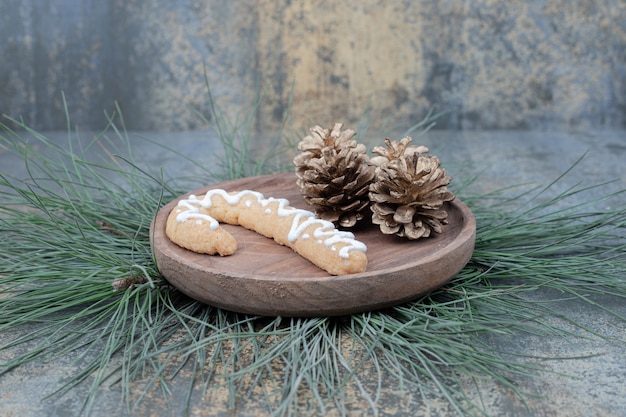 Free photo gingerbread cookie and pinecones on wooden plate. high quality photo