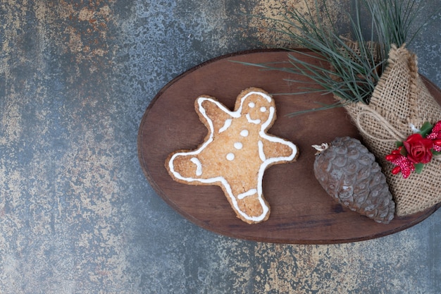 Gingerbread man cookie, pinecone and grasses in burlap on wooden plate. High quality photo