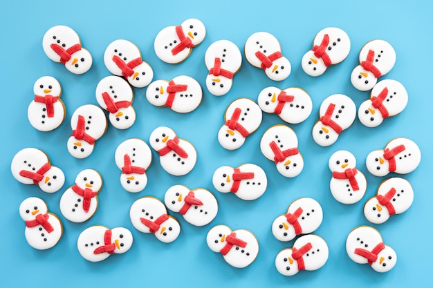 Free photo gingerbread snowmen covered with icing on a blue background flat lay