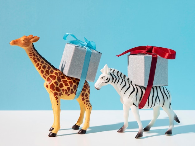 Free photo giraffe and zebra toys carrying gifts