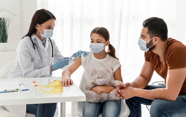 Girl being vaccinating next to her father