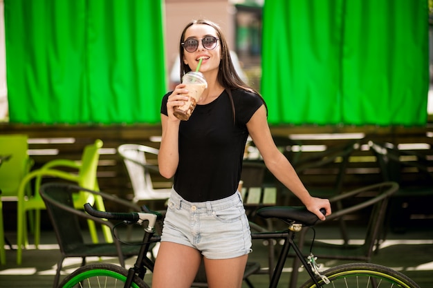 Free photo girl on a bicycle drinking coffee