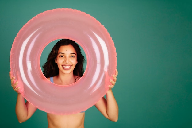 Free Photo girl in bikini looking through inflatable ring