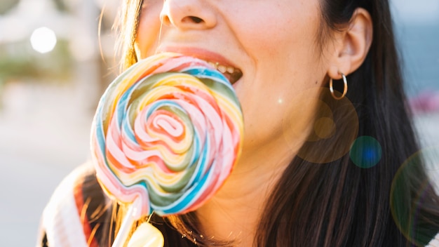 Girl bitting colorful lollipop