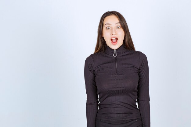 Girl in black clothes looking surprised and scared. 