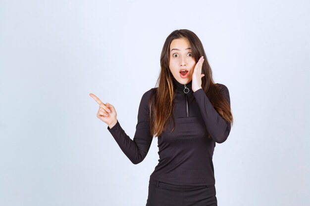 Girl in black clothes looking surprised and scared. 