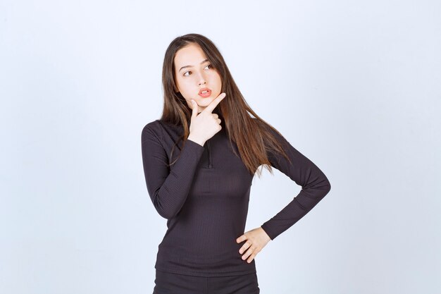 Girl in black clothes looks thoughtful and doubtful. 