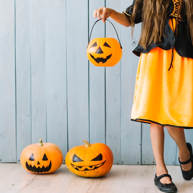 Free photo girl in black and orange dress standing and holding halloween basket