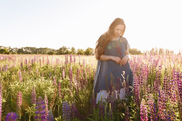 girl in blue dress walking in flower field. 