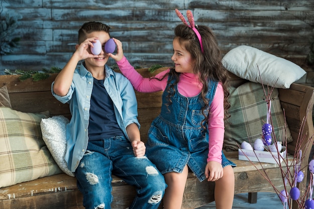 Free Photo girl and boy holding easter eggs at eyes