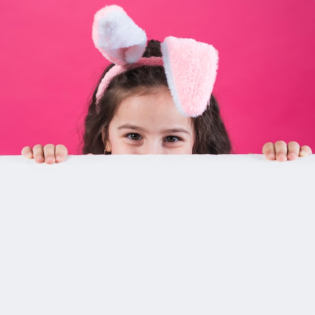 Girl in bunny ears hiding behind table