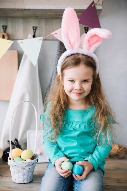 Free photo girl in bunny ears sitting with basket of easter eggs