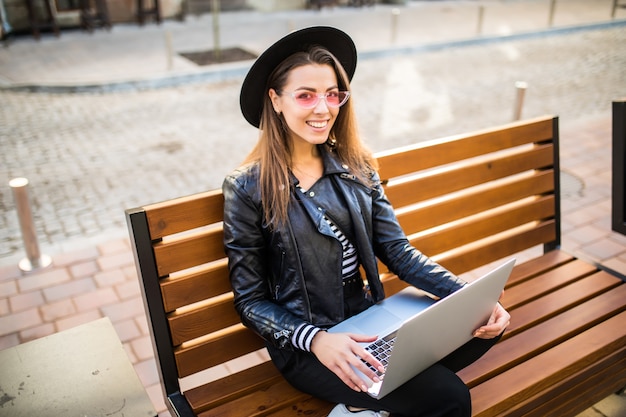 Girl business woman sit on wood bench in the city in the park in autumn