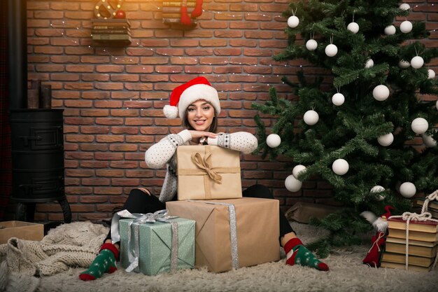 Girl by the Christmas tree unpacking gifts