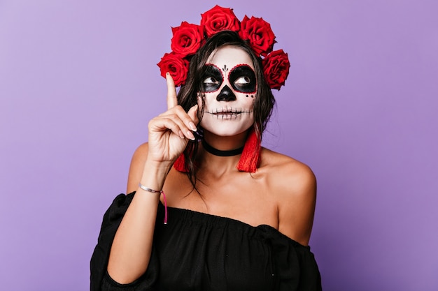 Free photo girl in carnival costume came up with funny idea. portrait of woman with roses in dark hair.