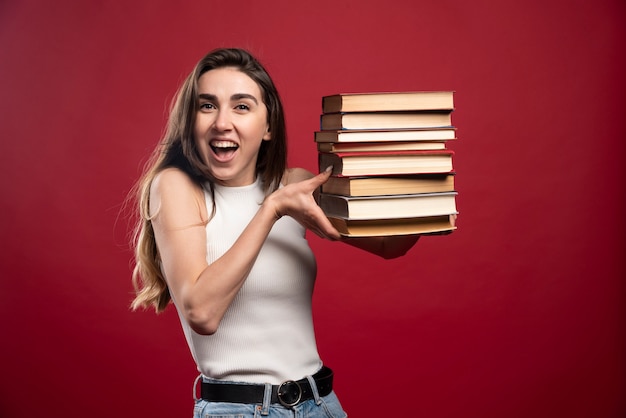 Free photo girl carries a heavy pile of books