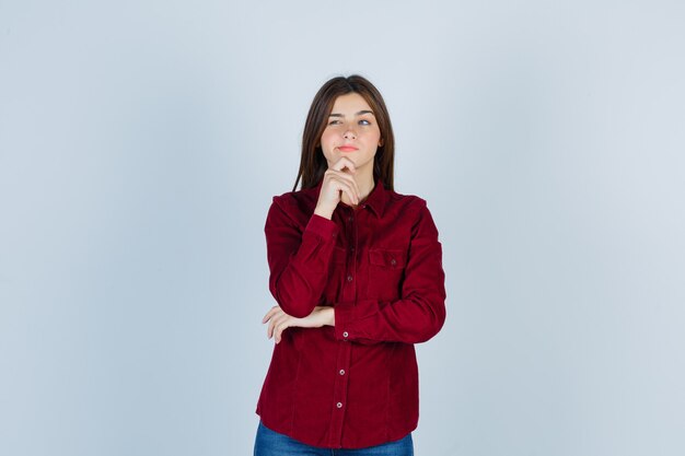 girl in casual shirt keeping finger on chin, looking away and looking thoughtful