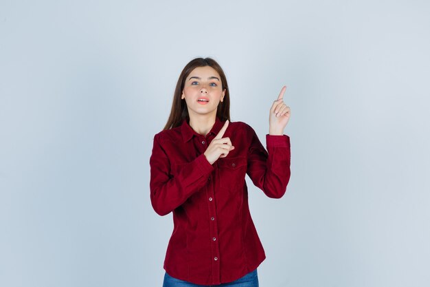 girl in casual shirt pointing up and looking curious