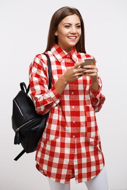 Girl in casual texting friends looking away smiling happily