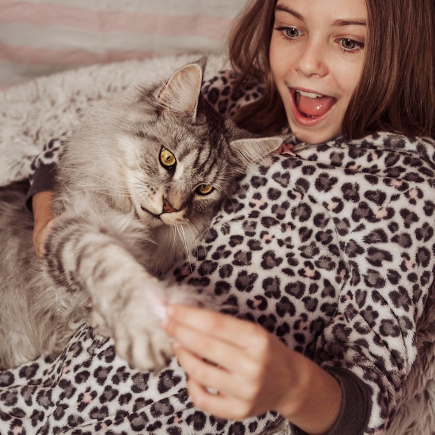 Free Photo girl and cat playing in the bed