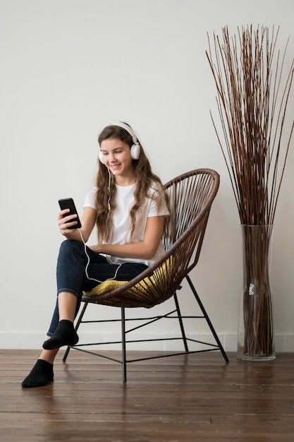 Girl on chair listening music at headphones