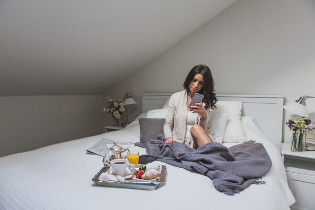 Girl checking her smartphone in the bed