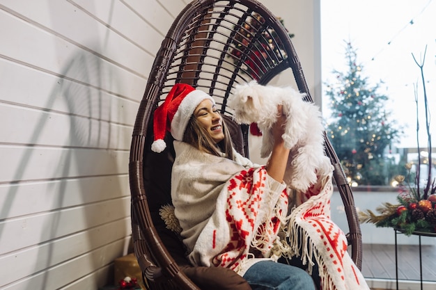 Free photo girl in a cocoon chair playing with her pet on new year's eve