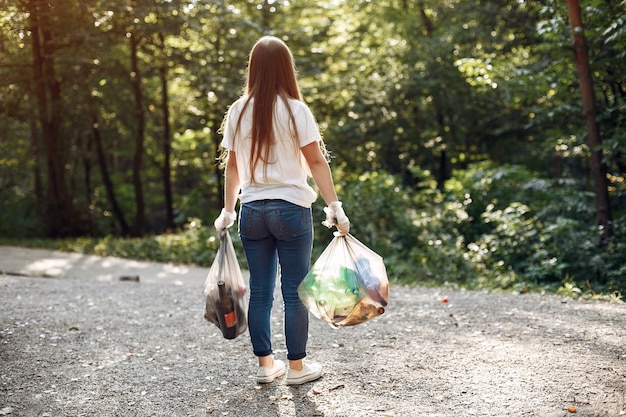 Girl collects garbage in garbage bags in park