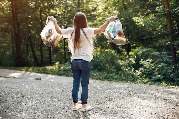 Girl collects garbage in garbage bags in park