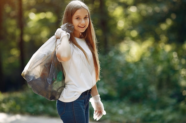 Free photo girl collects garbage in garbage bags in park