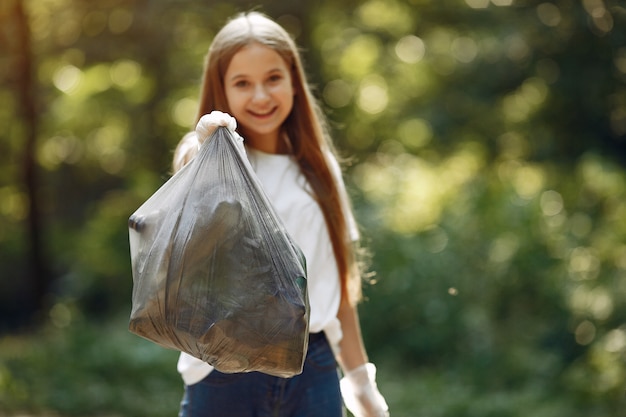 Girl collects garbage in garbage bags in park