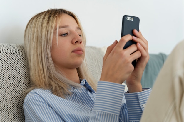 Girl on couch with smartphone medium shot