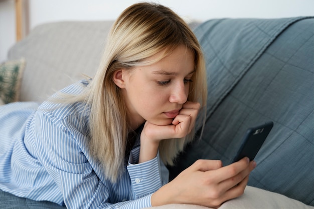 Girl on couch with smartphone side view