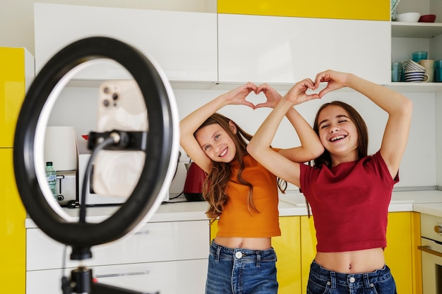 Free photo girl cousins spending time together at home and playing in front of ring light