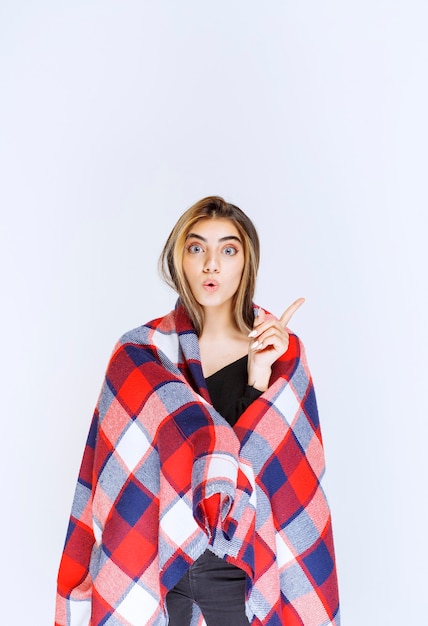 Free photo girl covered with red blanket pointing at something.