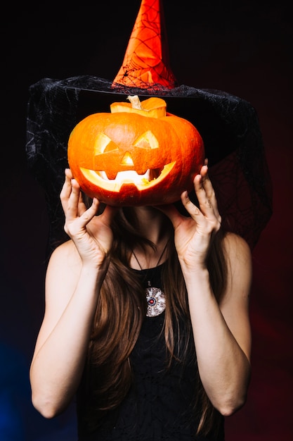 Free Photo girl covering face by pumpkin