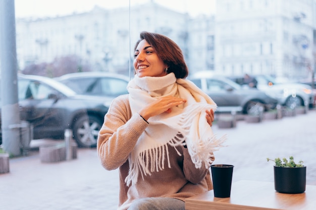 Free Photo a girl in a cozy cafe warms herself up with a cup of hot coffee