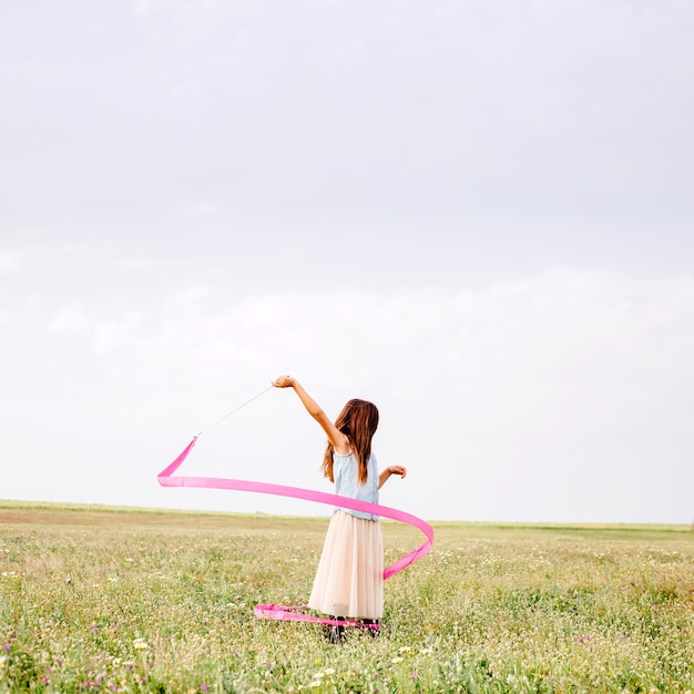 Free photo girl dancing with pink gymnastic ribbon