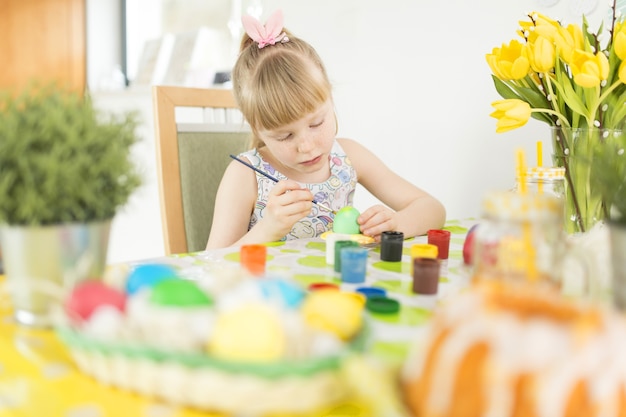 Girl decorating Easter eggs at table