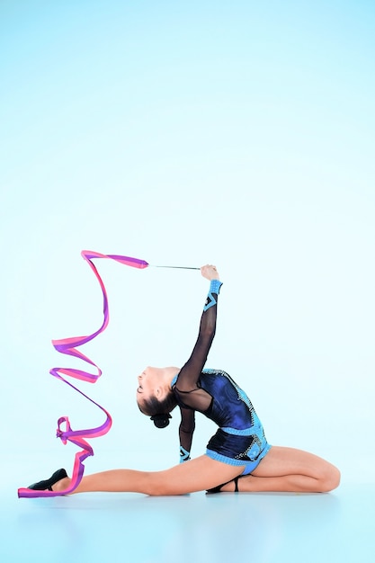 girl doing gymnastics dance with colored ribbon on blue