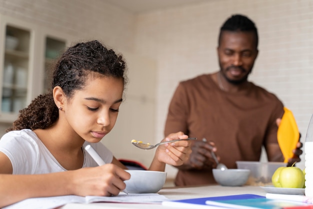 Girl doing her homework while having breakfast